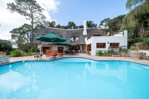 a swimming pool in front of a house at Plotsklaps Self Catering Cottage in Tokai