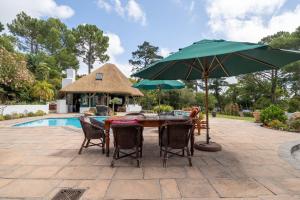 a table with chairs and an umbrella next to a pool at Plotsklaps Self Catering Cottage in Tokai