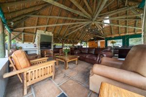 a living room with leather furniture and a wooden ceiling at Plotsklaps Self Catering Cottage in Tokai