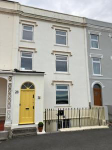 a white house with a yellow door and a fence at Lovely family seafront property in Burnham-on-Sea in Burnham on Sea