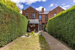 Breedon House 2 Bedroom Home in Long Eaton close to AIRPORT في لونغ إيتون: زقاق بين تحوط اثنين أمام مبنى