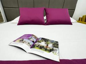 un libro sentado en una cama con almohadas moradas en Tevi Apartments, en Varna