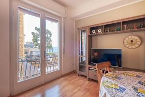 a living room with a television and a balcony at ApartmentsGarda - Residenza Dei Navigatori in Torri del Benaco