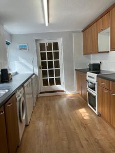 a kitchen with white appliances and wooden cabinets at Lovely family seafront property in Burnham-on-Sea in Burnham on Sea