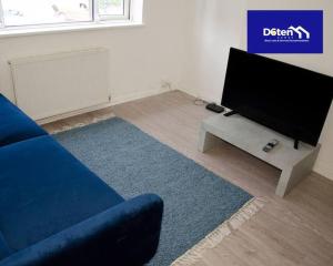 een woonkamer met een blauwe bank en een flatscreen-tv bij Sleeps 7x Weekly, Monthly Discounts x Free Parking in Forest Hill