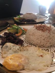 a plate of food with eggs and rice on a table at Portofino Homestay in Malitbog