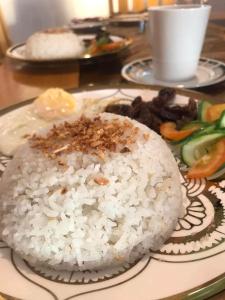 a plate of rice and vegetables on a table at Portofino Homestay in Malitbog