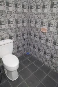 uma casa de banho com um WC e uma parede em azulejo em Ganeta Homestay Syariah 