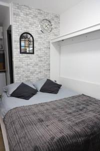sypialnia z łóżkiem i ceglaną ścianą z zegarem w obiekcie Le Cloudy - @Kreativehome_ w Rouen