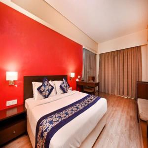 a bedroom with a large bed with a red wall at The Legend Hotel- Santacruz Near Mumbai International Airport in Mumbai