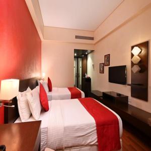 The Legend Hotel- Santacruz Near Mumbai International Airport في مومباي: غرفه فندقيه سريرين وتلفزيون