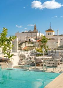 uma varanda com mesa e cadeiras e uma piscina em Vincci Molviedro Suites Apartments em Sevilha