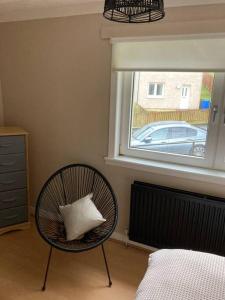 a room with a chair with a pillow and a window at Monthly/ weekly discounts, lovey apartment! in Clydebank