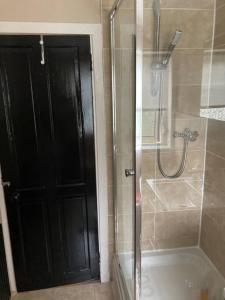 a bathroom with a shower and a black door at Monthly/ weekly discounts, lovey apartment! in Clydebank