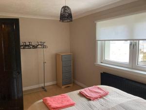 a bedroom with a bed with two pink towels on it at Monthly/ weekly discounts, lovey apartment! in Clydebank