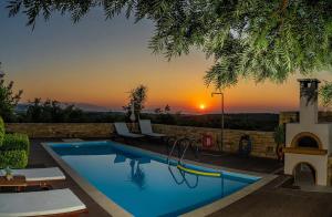 a swimming pool with a sunset in the background at Villa Callisto in Loutra