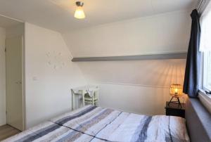 a white bedroom with a bed and a window at ALO43 renovated holiday home in Aagtekerke