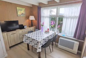 a dining room with a table with chairs and a window at ALO43 renovated holiday home in Aagtekerke