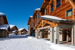 uma rua coberta de neve em frente a um alojamento de turismo selvagem em CGH Résidences & Spas White Pearl Lodge em La Plagne