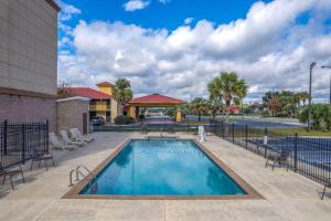 een zwembad met stoelen en een gebouw bij Baymont by Wyndham Savannah South in Savannah