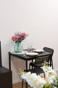 a black table with two chairs and a vase of flowers at Kwiatowa Apartments Poznań City Center by Renters in Poznań
