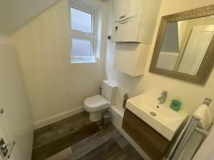 uma casa de banho com um WC, um lavatório e um espelho. em Light and Modern 2BR 1.5BA, newly refurbished! em Raynes Park