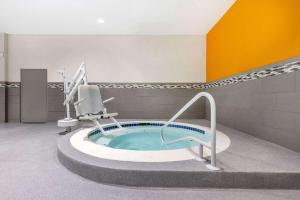 La Quinta Inn by Wyndham Lynnwood في لينوود: حمام مع حوض استحمام ساخن مع كرسي فيه