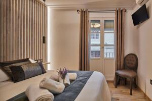 sypialnia z łóżkiem z krzesłem i oknem w obiekcie Little Sopranis Little Apartments w Kadyksie