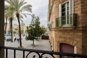 a balcony with a building and palm trees and a street at Little Sopranis Little Apartments in Cádiz