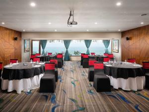 a conference room with tables and red chairs at The Bheemli Resort Visakhapatnam by AccorHotels in Visakhapatnam