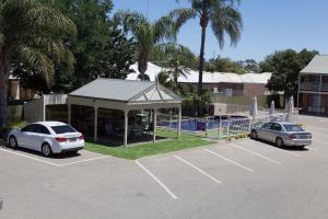 two cars parked in a parking lot with a gazebo at Paddlewheel Motel in Echuca