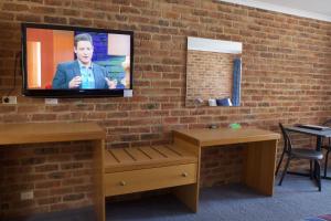 - une télévision sur un mur en briques avec un homme sur le mur dans l'établissement Paddlewheel Motel, à Echuca