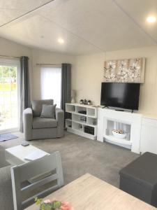uma sala de estar com uma televisão de ecrã plano e um sofá em Cumbria Reach em Longtown