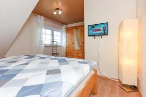 1 dormitorio con 1 cama y TV en la pared en Ferienwohnungen Haus Wiesen- und Waldblick, en Esens