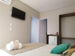 um quarto com uma cama e uma televisão de ecrã plano na parede em Bless em Maragogi