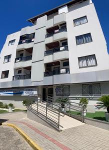 ein großes weißes Gebäude mit Bäumen davor in der Unterkunft Hermoso departamento en Bombas con vista al mar in Bombinhas + 10 Fotos