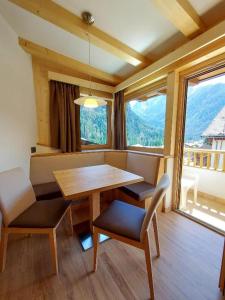 a dining room with a table and chairs and windows at Albergo Arnica in Canazei