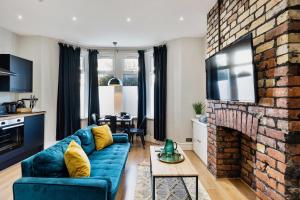 a living room with a blue couch and a brick fireplace at Stylish modern apartment near the city centre with nearby off-road parking in Cardiff +24 photos