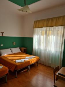 two beds in a room with green walls and curtains at B&B Santa Lucia in San Giovanni Rotondo