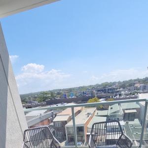 a balcony with two chairs and a view of a city at Spectacular Waterfront Views Discover the Hidden Gem of Cronulla with our Rare 3 Bedroom Apartment with Free Parking in Cronulla