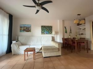 ein Wohnzimmer mit einem weißen Sofa und einem Deckenventilator in der Unterkunft Apartamentos Arcos Calabardina in Calabardina