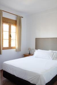a bedroom with a large white bed with a window at Hotel Tugasa El Almendral in Setenil