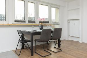 uma sala de jantar com mesa, cadeiras e janelas em Ochota Spacious Apartment with Parking by Renters em Varósvia