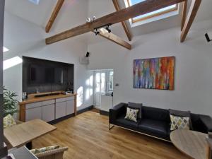 sala de estar con sofá negro y TV de pantalla plana en Seashells at 2 TRENCROM COURT ST IVES en Carbis Bay