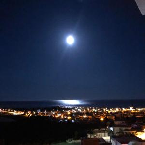 uma lua cheia a subir sobre uma cidade à noite em Casa Luna - Sea view apartment Bolnuevo em Bolnuevo
