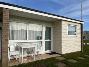 a small house with a table and chairs on a patio at Bermuda Haven 26, Hemsby - Two bed chalet, sleeps 5, pet free site, onsite entertainment in Great Yarmouth