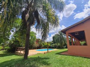 a palm tree next to a house with a swimming pool at Chácara Santo Antonio in Brotas