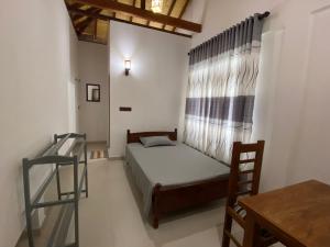 a small bedroom with a bed and a window at Berty's Cottage in Jaffna