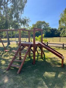 un parque infantil de madera con un tobogán en un parque en Cabañas Puesta del Sol en Las Flores