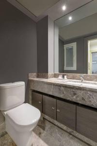 een badkamer met een toilet, een wastafel en een spiegel bij Panoramic 1BR Apartment near Kallimarmaro Stadium by UPSTREET in Athene